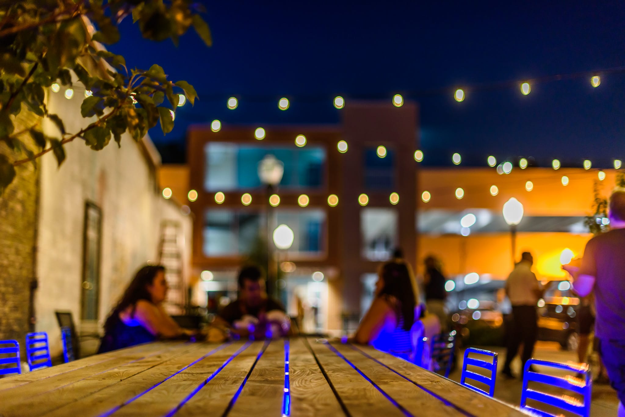 Outdoor dining at night with string lights and blurred people.